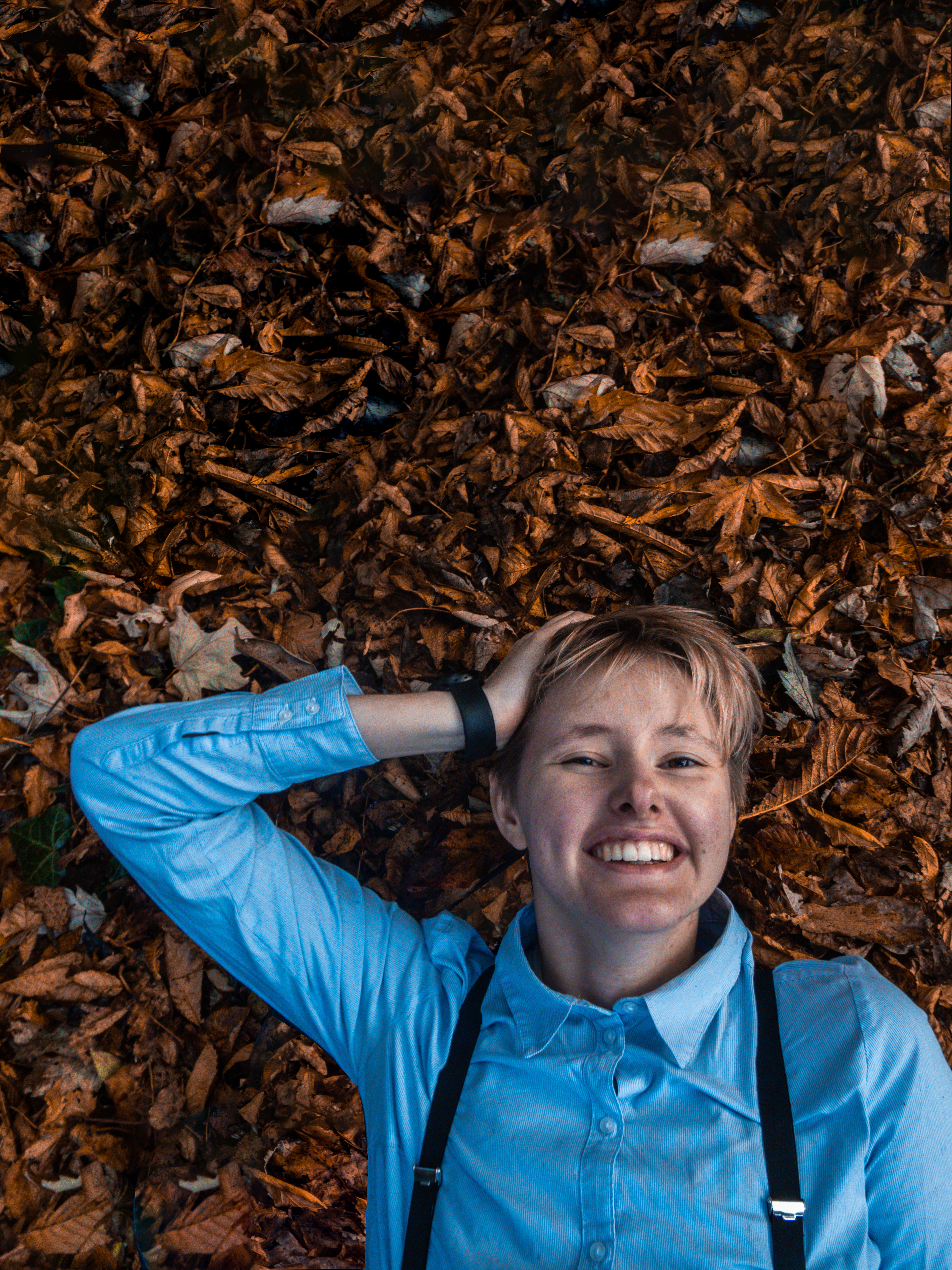 Een foto van Leo die in allerlei herfst bladeren ligt.